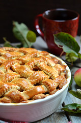 American apple pie in white baking form on a wooden background