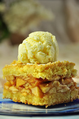 A piece of traditional apple pie with a ball of ice cream on top