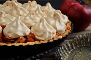 Tart with meringue in a black mold on a wooden background