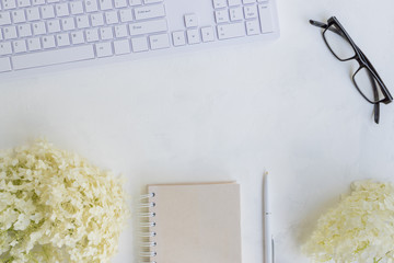 Blogger or freelancer workspace with notebook and white flower hydrangea