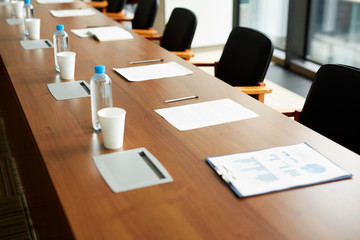 Close-up of drinking water in bottles, papers and pens on conference table prepared for business educational event