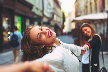 Two young happy women in the city - obrazy, fototapety, plakaty