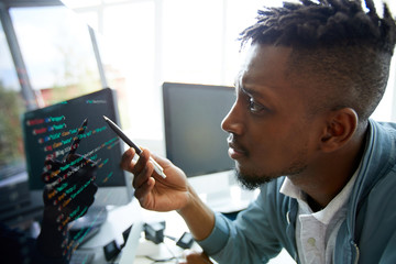 Serious concentrated young African-American programmer looking confused while learning coding...