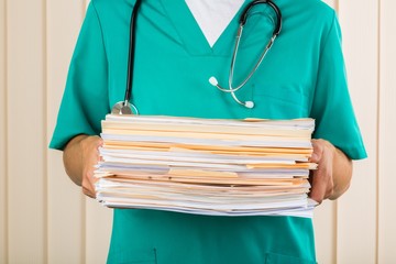 Close-up of a Nurse with Stack of Documents / Files - obrazy, fototapety, plakaty