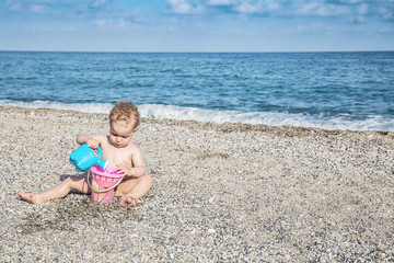 Naklejka premium Lovely baby boy playing with beach toys