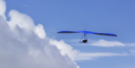 Fototapeta na wymiar Hang Glider flying in the sky on a sunny bright blue day