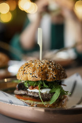 Close up of fresh burger with other burger on background in cafe.