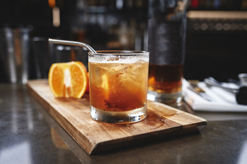 a close up of ice cold modern gourmet cocktail of bourbon garnished by orange slices on a bar in a restaurant