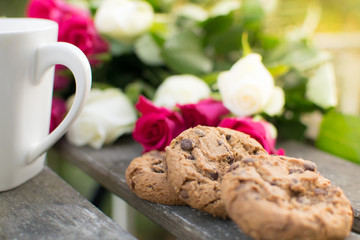 Close up image of chocolate chip cookies with roses in the background