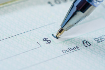 Black pen writing dollar amount on banking check