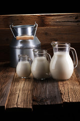 A jug of milk and glass of milk on a wooden table
