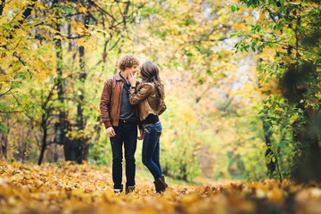 Loving couple kissing among beautiful autumn maples.