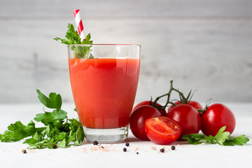 Tomato juice with fresh tomatoes, parsley, sea salt and pepper on light grey background. Vegetable drink.