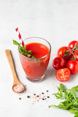 Tomato juice with fresh tomatoes, parsley, sea salt and pepper on light grey background. Vegetable drink.