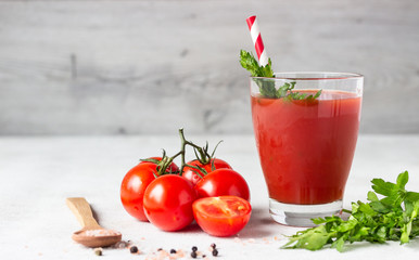 Tomato juice with fresh tomatoes, parsley, sea salt and pepper on light grey background. Vegetable drink.