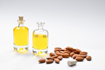 Bottles of almond oil and almonds  on white background, copyspace.