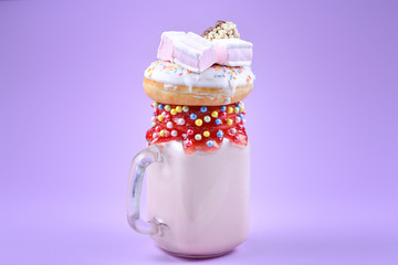 Pink strawberry freakshake with marshmallow and sweets.