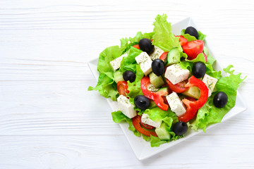 Greek salad on a white wooden background. Space for text or design.