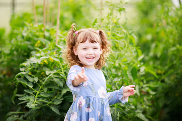 Adorable happy little smiling girl in the greenhouse