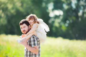 Portrait of a happy father and a beautiful little girl wearing angel costume
