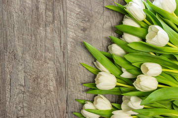 white tulips with green leaves on a wooden background. birthday. mothers Day. Christmas. Valentine's Day.