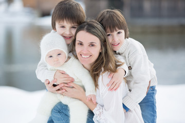 Obraz premium Beautiful mother in white dress and her cute children, three boys