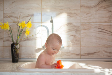 Sweet baby boy, taking shower in sink in kitchen, morning time