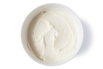 Cream cheese in a bowl, isolated on white background, top view.