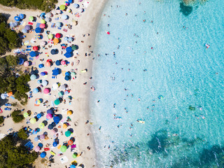 Fototapeta na wymiar View from above, aerial view of an emerald and transparent Mediterranean sea with a white beach full of beach umbrellas and tourists who relax and swim. Costa Smeralda, Sardinia, Italy.