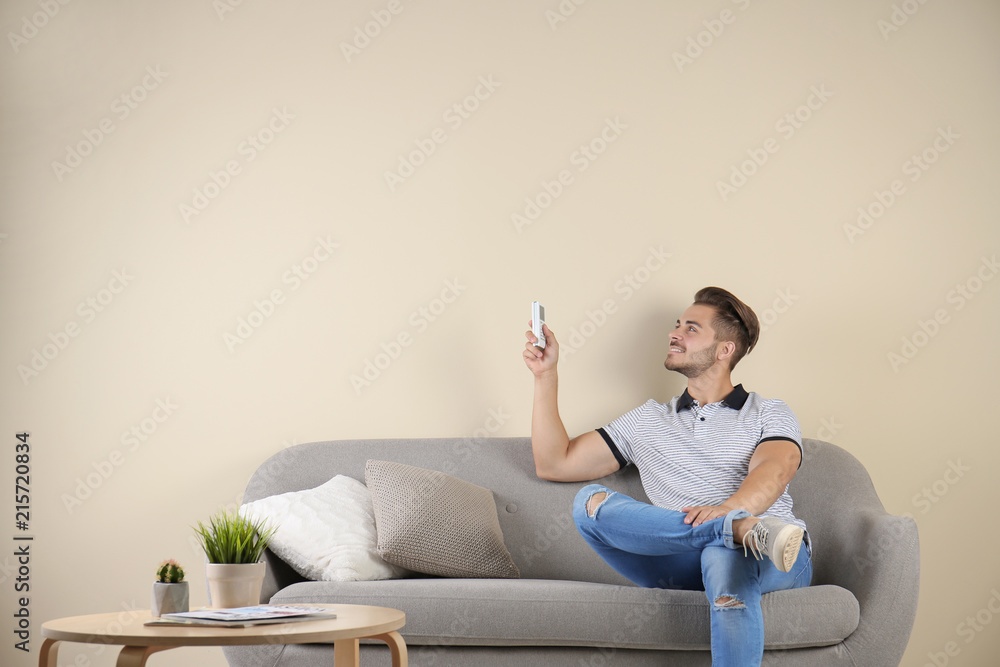 Sticker young man with air conditioner remote at home