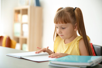 Cute little child doing assignment at desk in classroom. Elementary school