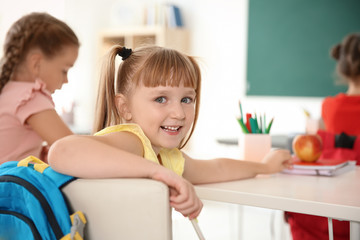 Cute little child sitting at desk in classroom. Elementary school