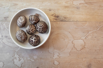 Small bowl of dried shiitake mushrooms on a weathered wood tabletop, copy space, horizontal aspect