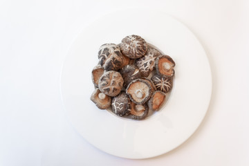 Wide rimmed bowl filled with shiitake mushrooms, isolated on white, horizontal aspect