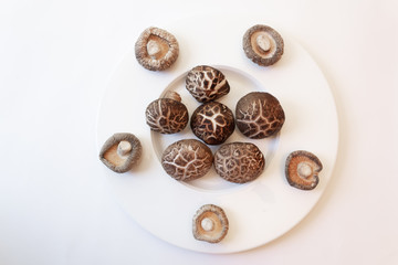 Wide rimmed bowl with shiitake mushrooms viewed from overhead and beneath, isolated on white, horizontal aspect