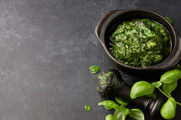 Basil pesto sauce with parmesan cheese, nuts, olive oil and garlic in black cast iron mortar, close up view