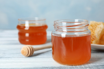 Glass jar with sweet honey and dipper on table, closeup