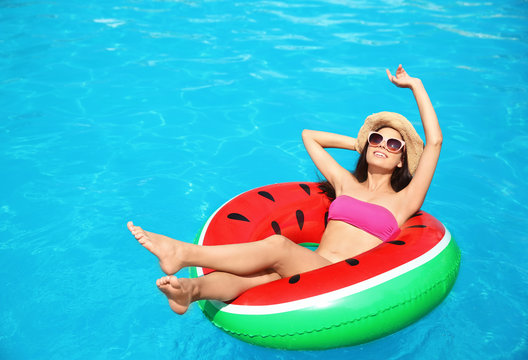 Beautiful young woman with inflatable ring in swimming pool