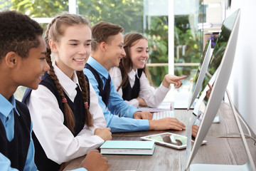 Teenage students in stylish school uniform at desks with computers