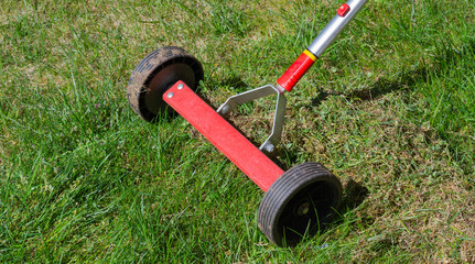 Cleaning up the grass with a rake. Aerating and scarifying the lawn in the garden. Remove old grass. Manual scarification of lawn with fan rakes and wheels. 