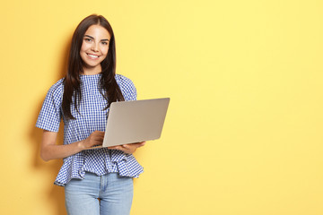 Naklejka premium Young woman with modern laptop on color background