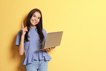 Fototapeta premium Young woman with modern laptop on color background