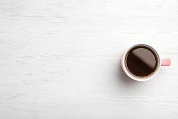 Ceramic cup with hot aromatic coffee on wooden background, top view