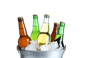 Bottles with different types of beer and ice in metal bucket on white background