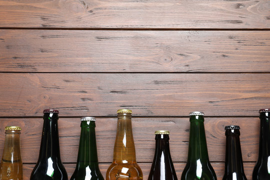 Bottles with different types of beer on wooden background