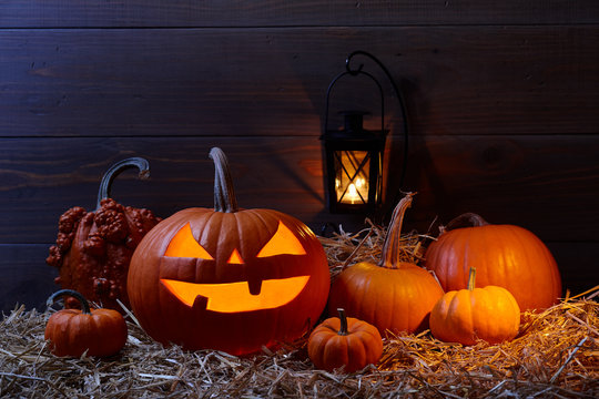 Carved pumpkin jack lantern and pumpkins in dark barn, Halloween holiday celebration concept