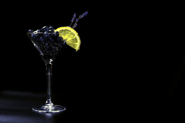 Cocktail with bluberriy in martini glass on black background