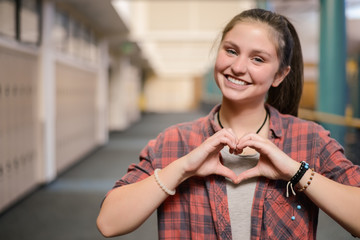Teen girl showing heart hands at high school