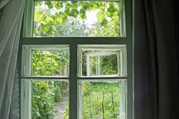 old gray window with curtains in the room on a bright summer day