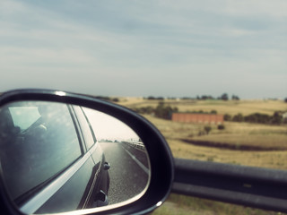 Car Trip. View of Side Mirror and Countryside in the Background (Vintage Style)